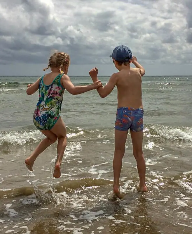 boy and girl jumping in waves