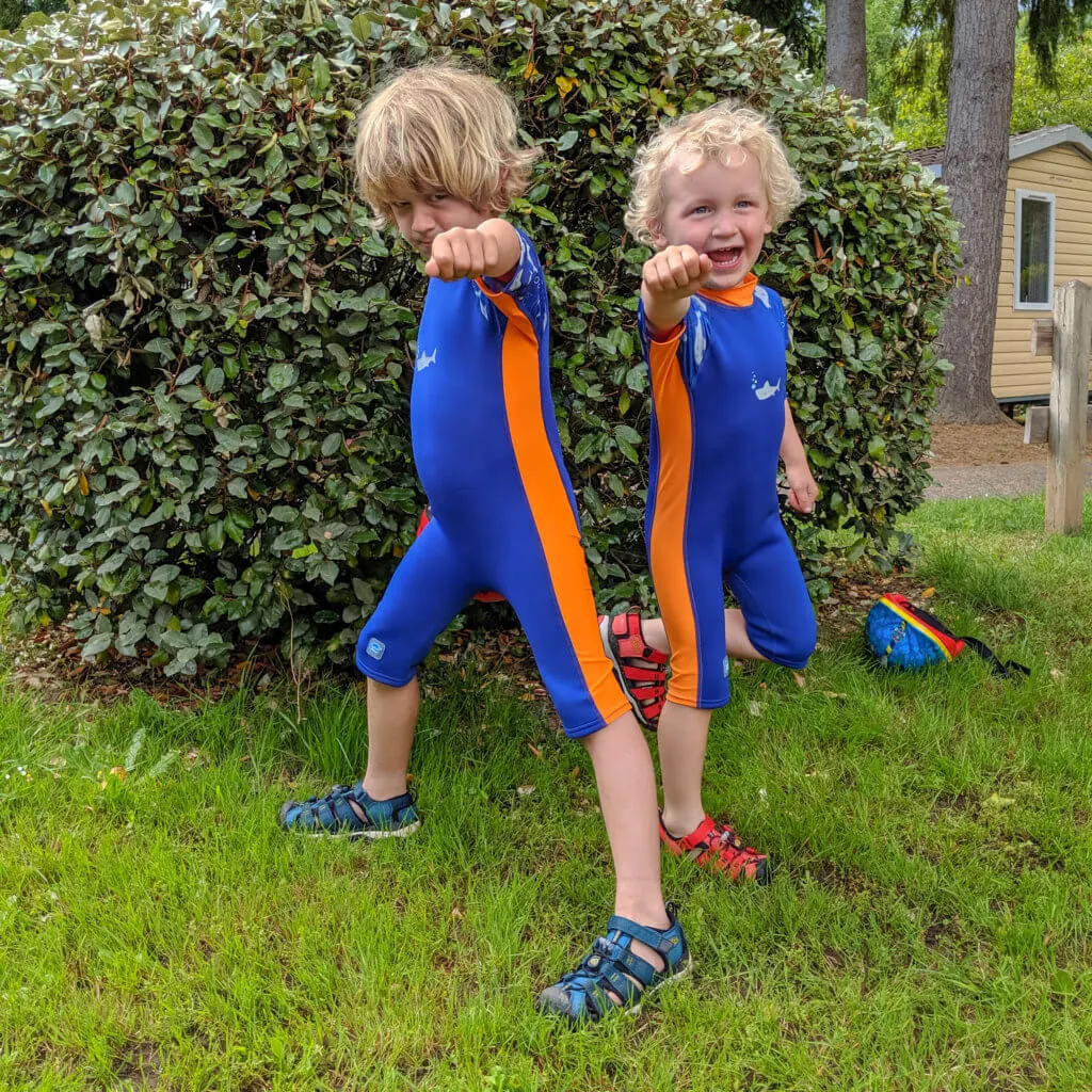 two boys by hedge in wetsuits