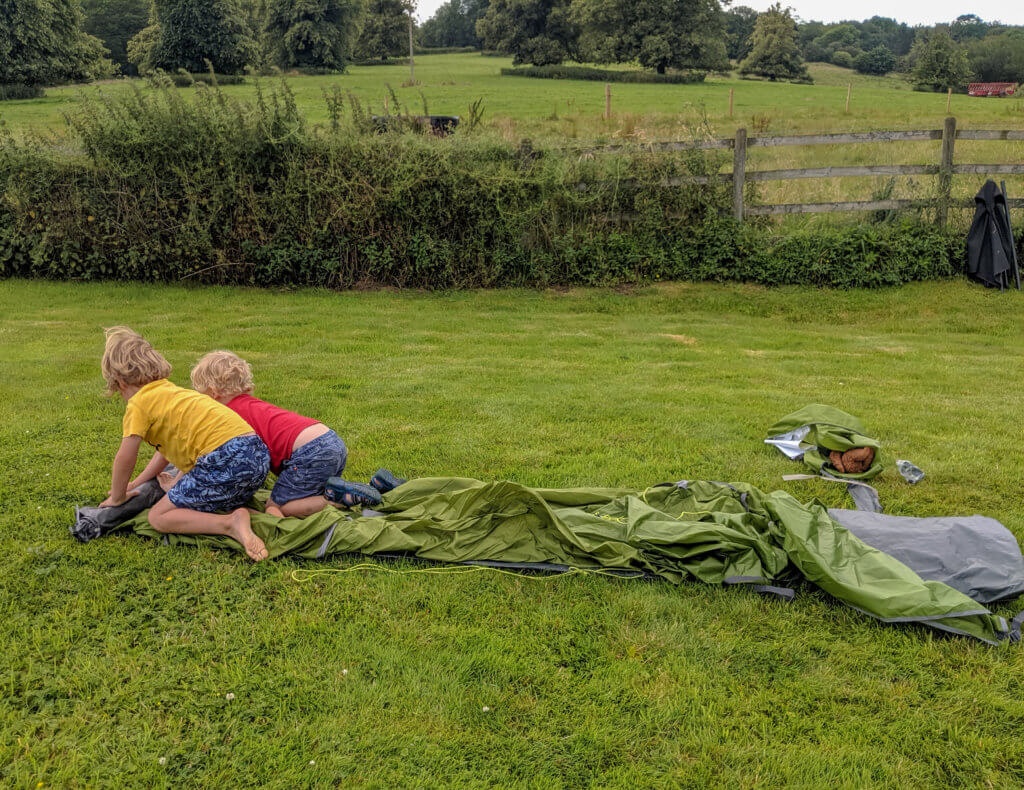 two boys rolling out a tent