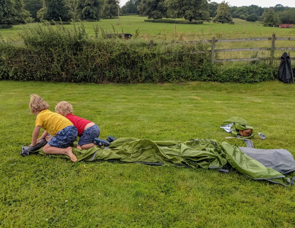 two boys rolling out a tent