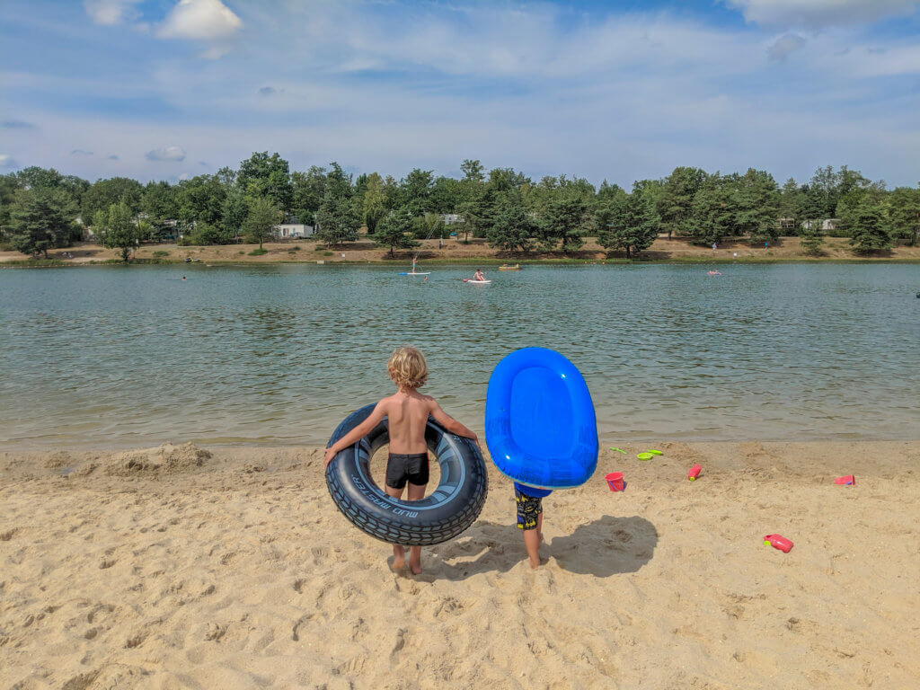 boys stood on sandy beach by lake