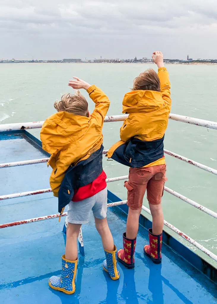 boys waving goodbye to France from the Dover to Calais ferry